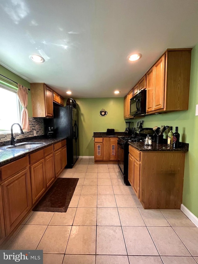 kitchen featuring backsplash, brown cabinetry, light tile patterned flooring, a sink, and black appliances