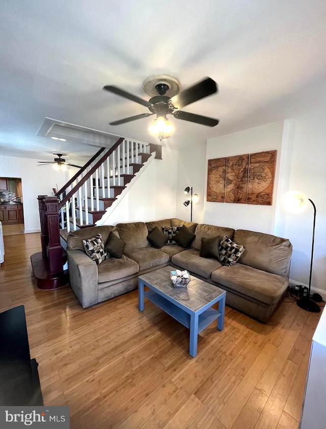 living area featuring attic access, stairs, a ceiling fan, and wood finished floors