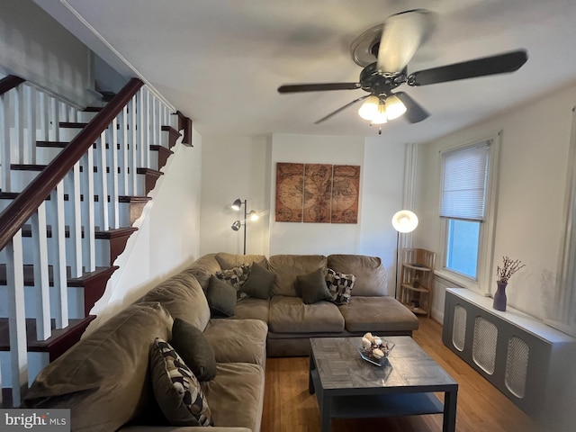 living area featuring stairs, a ceiling fan, and wood finished floors