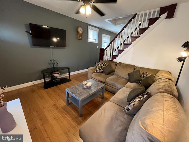 living room featuring stairs, a ceiling fan, baseboards, and wood finished floors