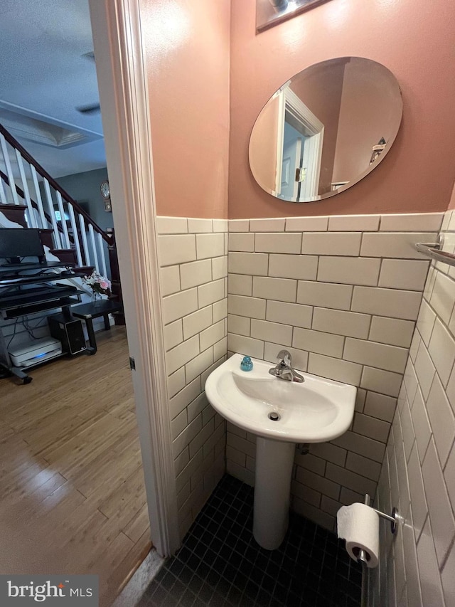 bathroom with a wainscoted wall, tile walls, and wood finished floors