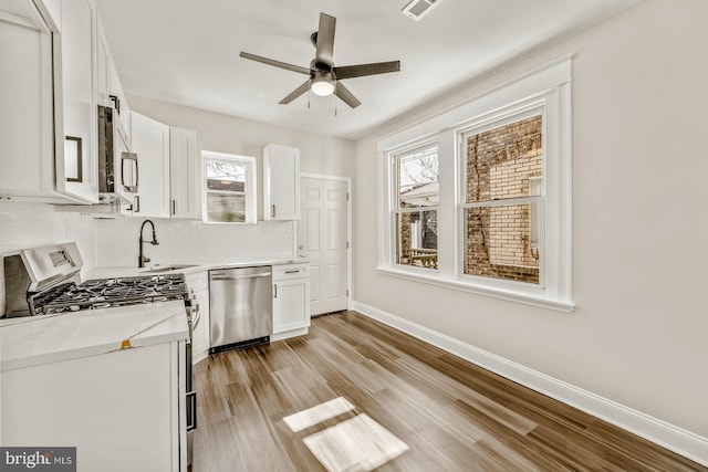 kitchen with white cabinetry, appliances with stainless steel finishes, light wood-style flooring, and a sink