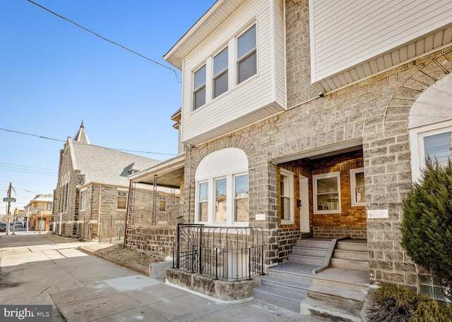 doorway to property with covered porch and stone siding