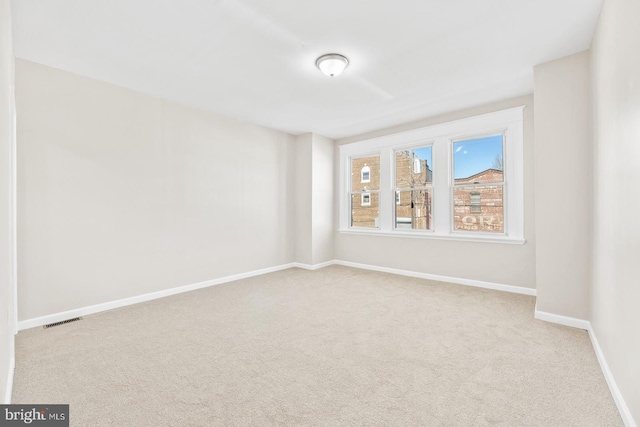 empty room featuring carpet floors, visible vents, and baseboards