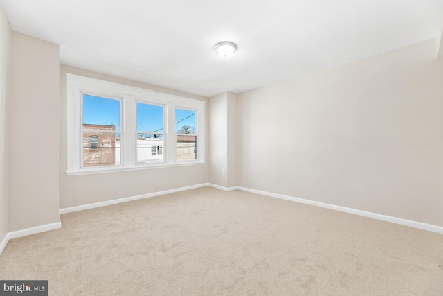 spare room featuring carpet floors and baseboards