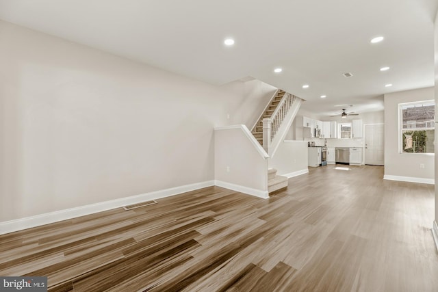 unfurnished living room with light wood finished floors, baseboards, visible vents, stairs, and recessed lighting