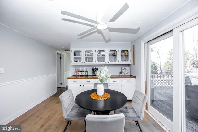 dining area with light wood-style flooring, a ceiling fan, and baseboards