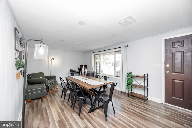 dining space featuring light wood-style flooring, visible vents, and baseboards