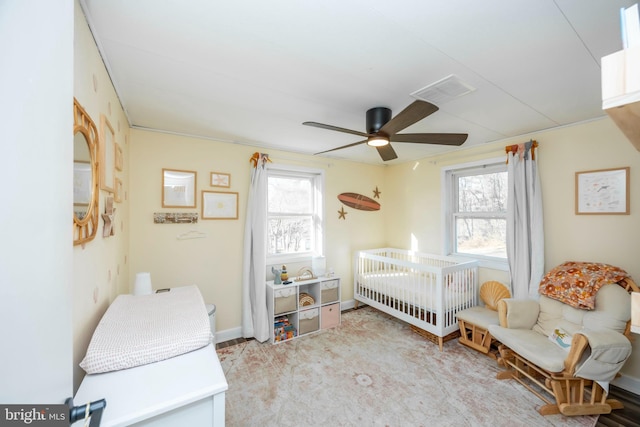 carpeted bedroom featuring visible vents, multiple windows, baseboards, and a ceiling fan