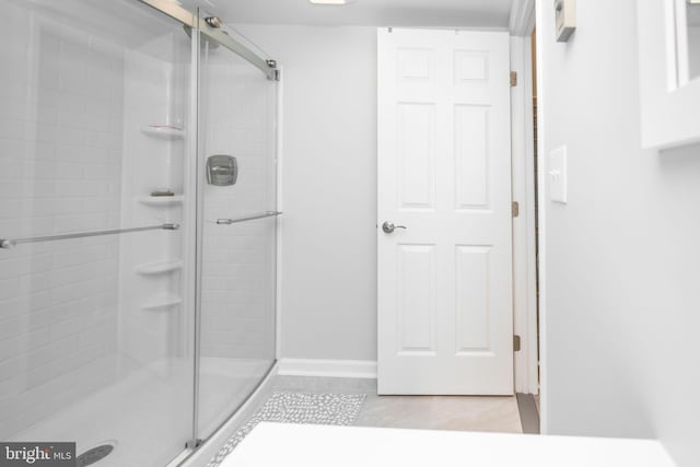 bathroom with tile patterned flooring, a shower stall, and baseboards