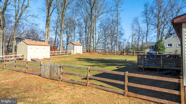 view of yard with a fenced backyard, a shed, a wooden deck, and an outdoor structure