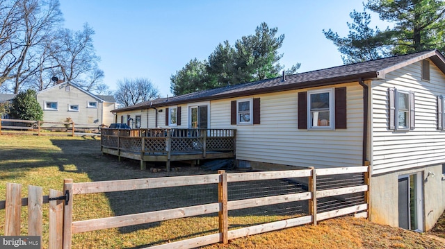 rear view of property with a deck, fence private yard, and a lawn