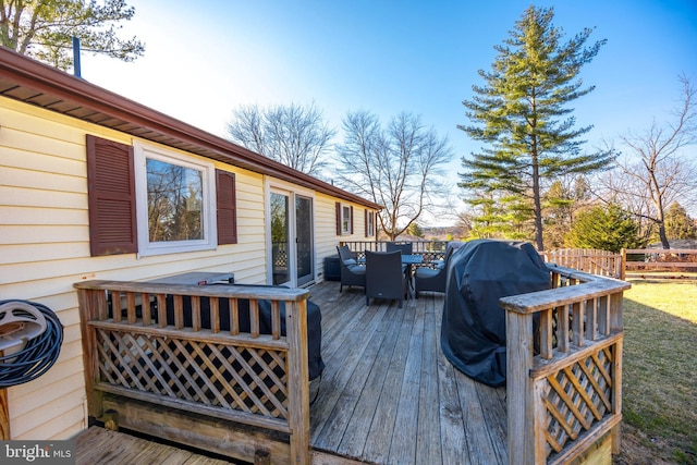 wooden terrace with outdoor dining space, grilling area, and fence