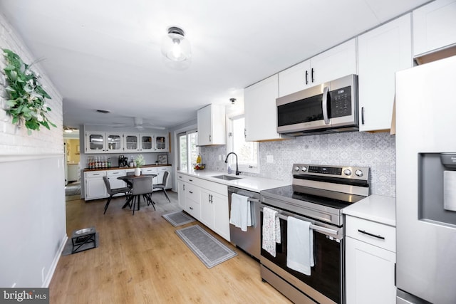 kitchen with decorative backsplash, white cabinetry, stainless steel appliances, and a sink