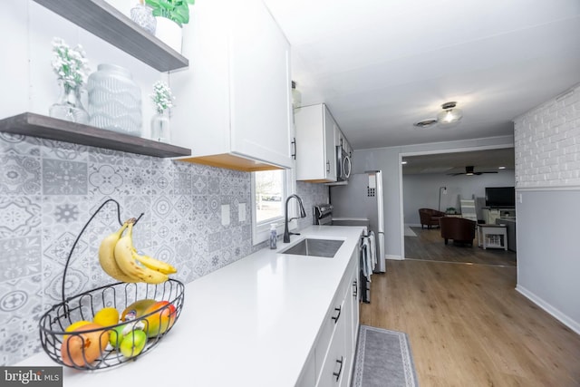 kitchen with open shelves, a sink, light wood-style floors, white cabinetry, and tasteful backsplash