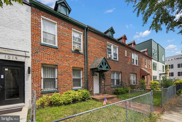 view of property featuring a fenced front yard, cooling unit, and brick siding