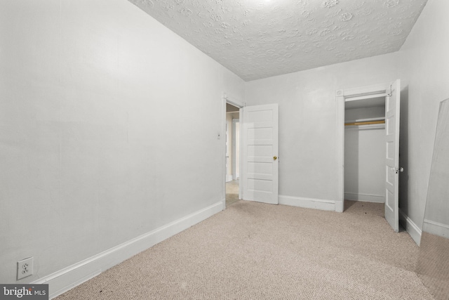 unfurnished bedroom featuring carpet, a closet, a textured ceiling, and baseboards