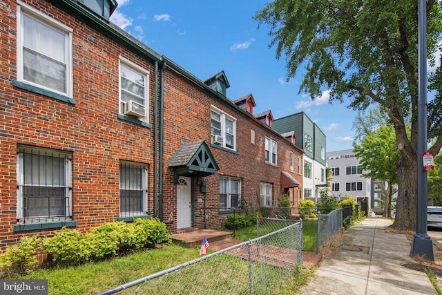 exterior space featuring brick siding, a fenced front yard, and cooling unit