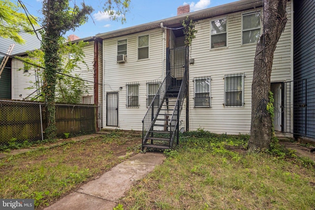 view of front facade with stairway, a chimney, fence, and cooling unit