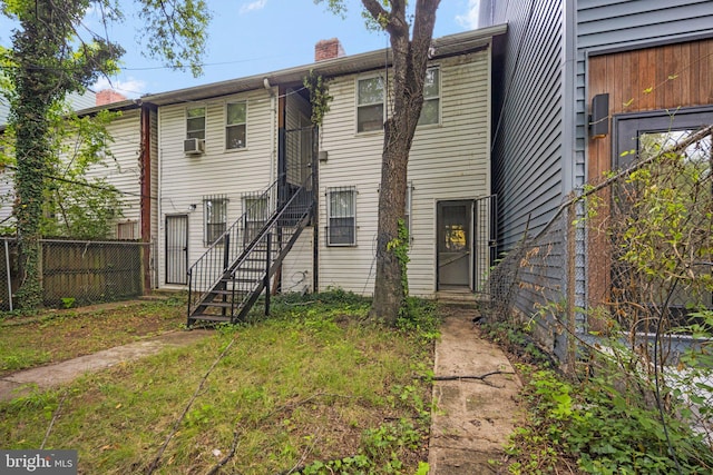 view of front of home with a chimney, cooling unit, and fence