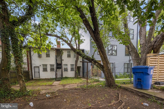 back of house featuring stairway, a chimney, and fence