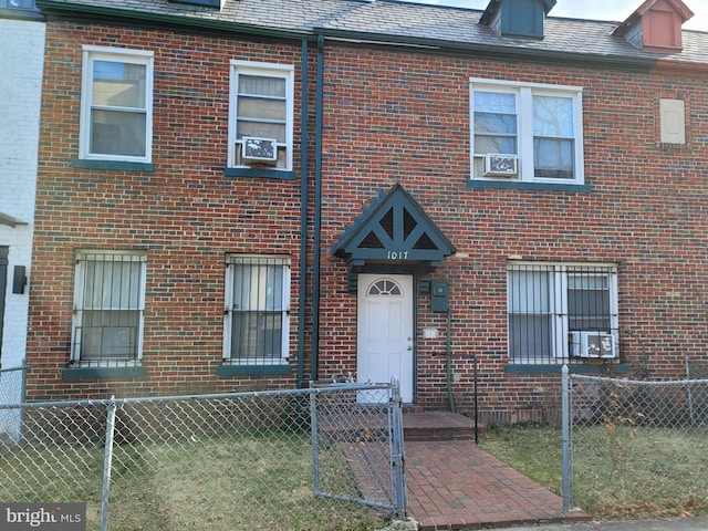 view of front of property featuring a fenced front yard, a high end roof, and brick siding