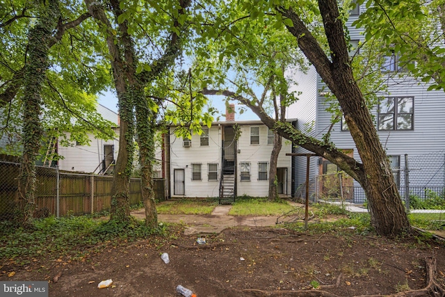 rear view of property featuring stairway, a chimney, and fence