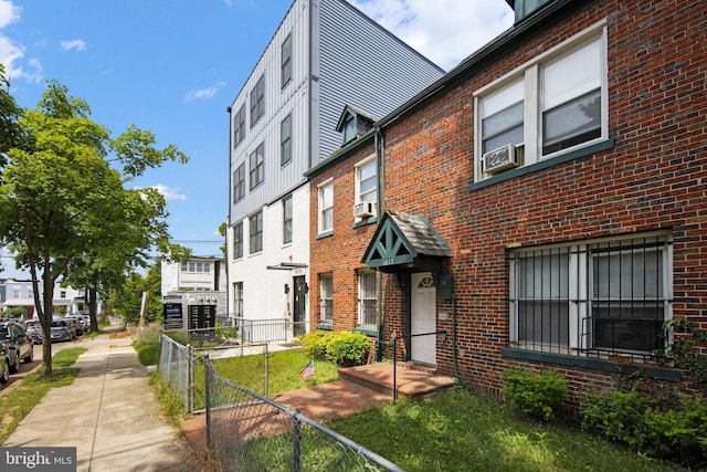 view of front of house featuring fence, cooling unit, and brick siding