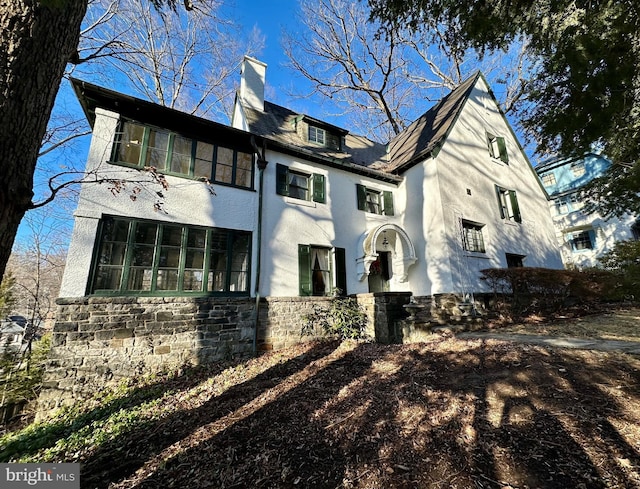 view of front facade with stone siding and a chimney