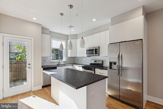 kitchen with visible vents, light wood finished floors, a sink, stainless steel appliances, and backsplash