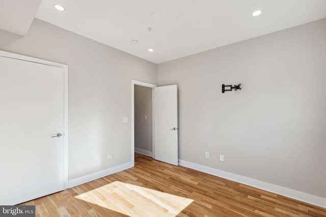 unfurnished bedroom with recessed lighting, wood finished floors, and baseboards