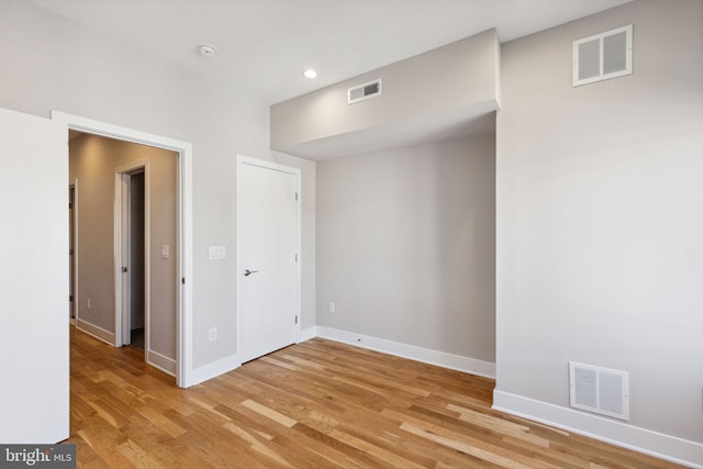 empty room featuring visible vents, baseboards, and light wood-style floors