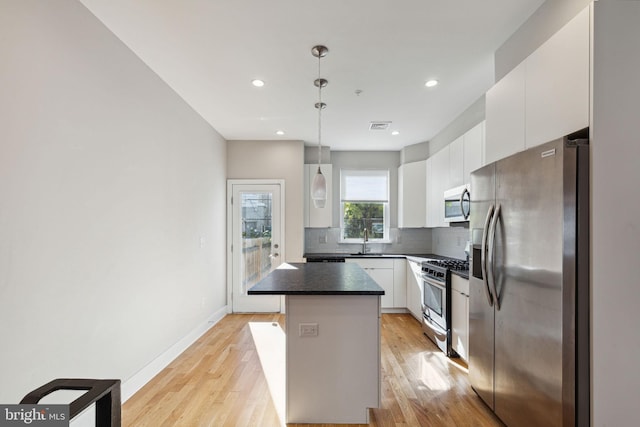 kitchen featuring a sink, decorative backsplash, white cabinetry, and stainless steel appliances