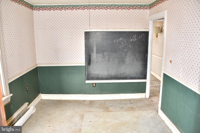 empty room featuring a wainscoted wall, a baseboard radiator, wallpapered walls, and carpet flooring