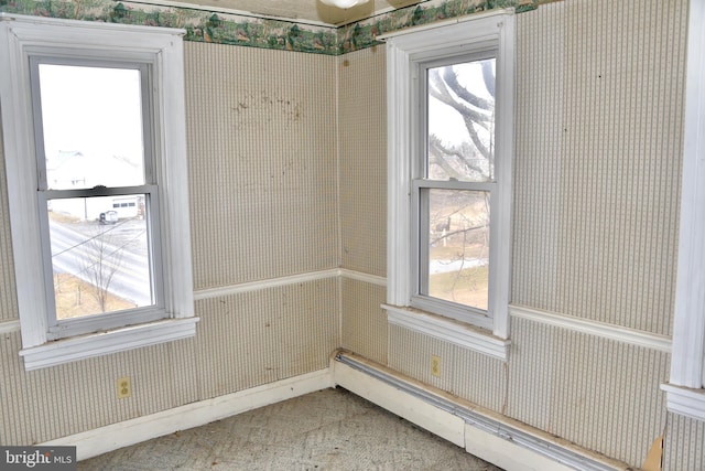 empty room with a healthy amount of sunlight, baseboard heating, and wallpapered walls