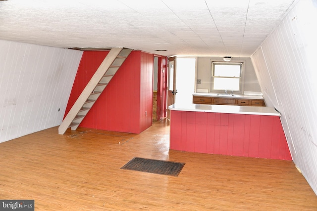 kitchen with visible vents, a sink, a peninsula, and wood finished floors