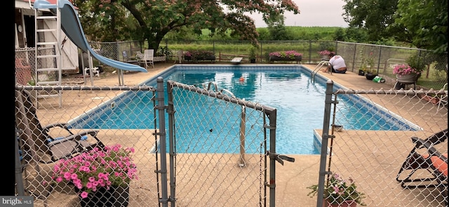 view of pool with a fenced in pool, a gate, fence, a water slide, and a diving board