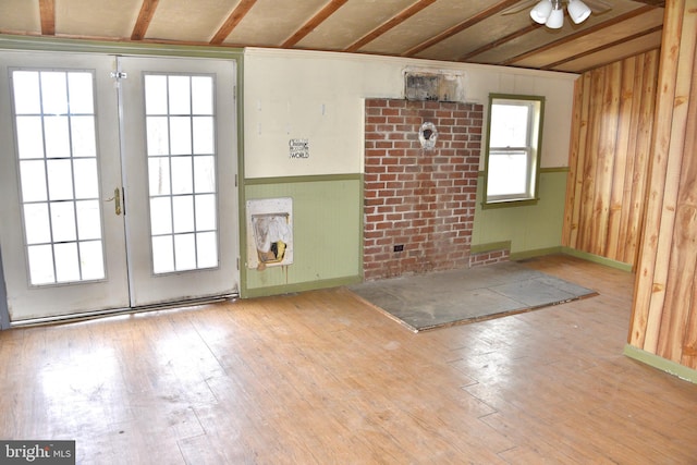 empty room featuring wainscoting, wood-type flooring, heating unit, french doors, and wood walls