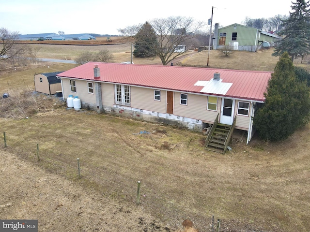 view of front of home featuring entry steps, metal roof, and a front lawn