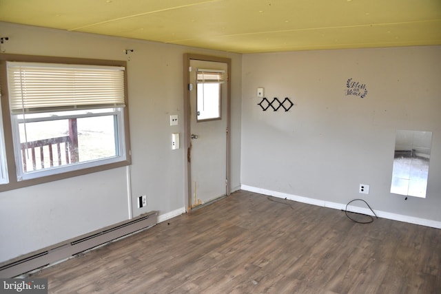 unfurnished room featuring a healthy amount of sunlight, baseboard heating, and wood finished floors