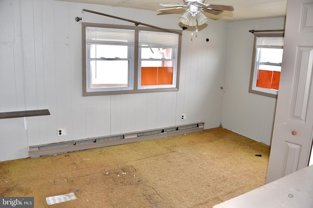 empty room with a baseboard heating unit, a ceiling fan, and a healthy amount of sunlight