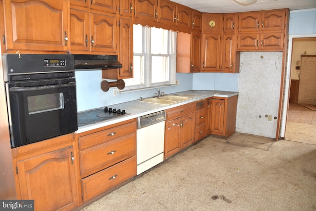 kitchen with brown cabinetry, under cabinet range hood, light countertops, black appliances, and a sink