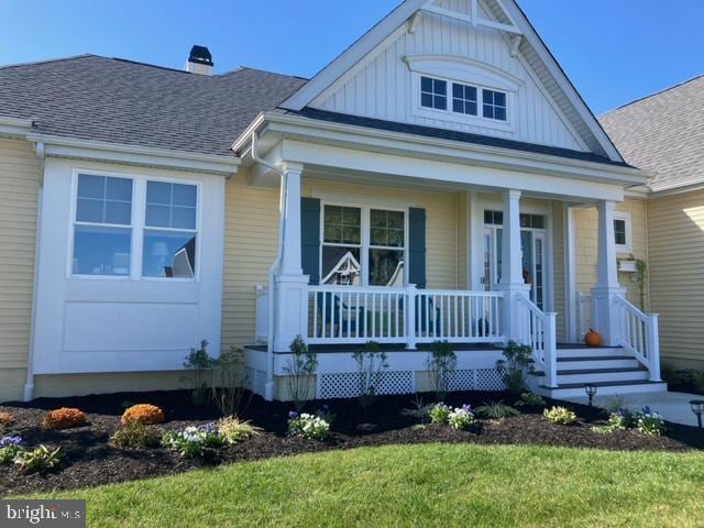 view of front of house featuring covered porch, a shingled roof, and a chimney