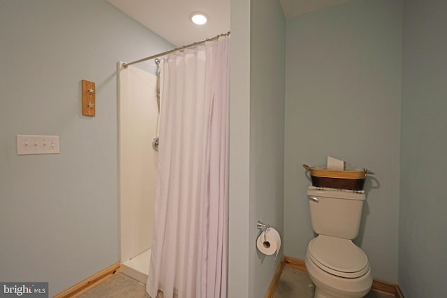 bathroom with toilet, a shower with curtain, and baseboards