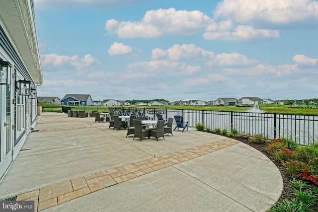 view of patio / terrace with a water view, fence, and a residential view