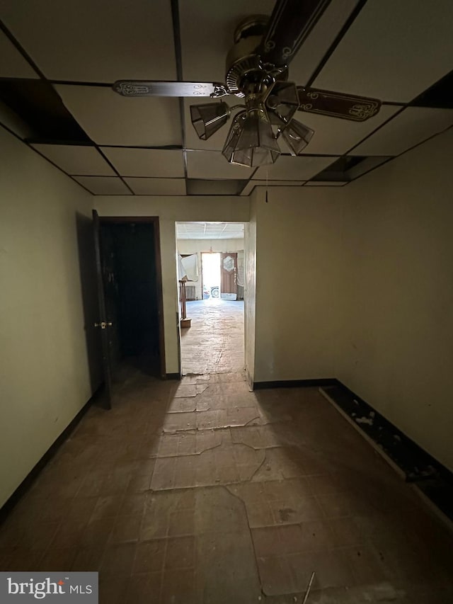 hall featuring a paneled ceiling and baseboards