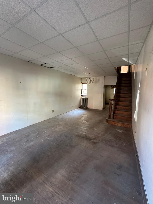 basement with a paneled ceiling and stairs