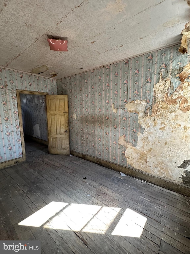 empty room featuring wood-type flooring and baseboards