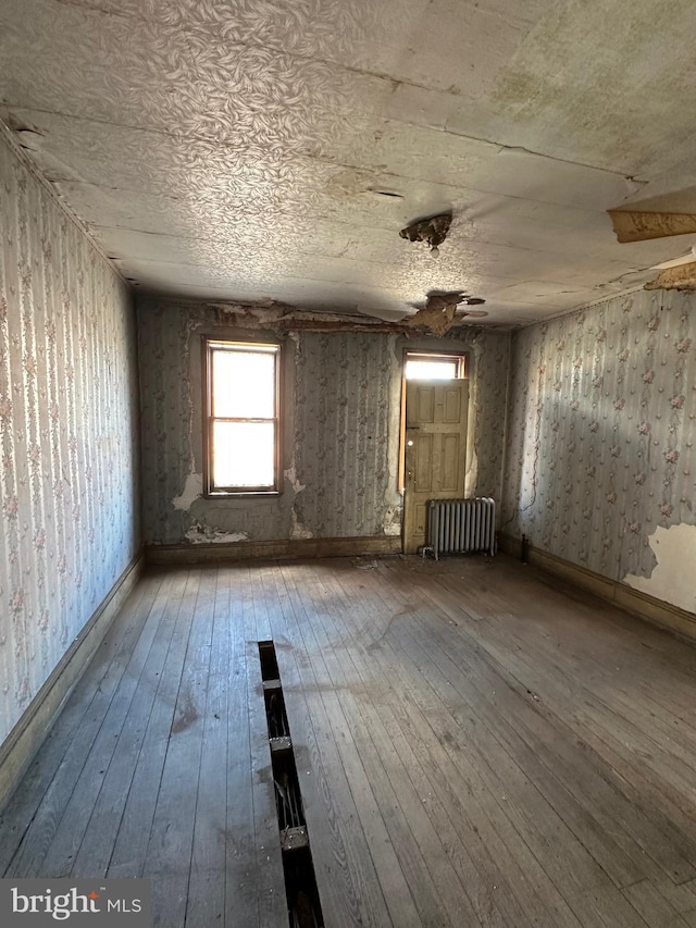 misc room with baseboards, wood-type flooring, and radiator