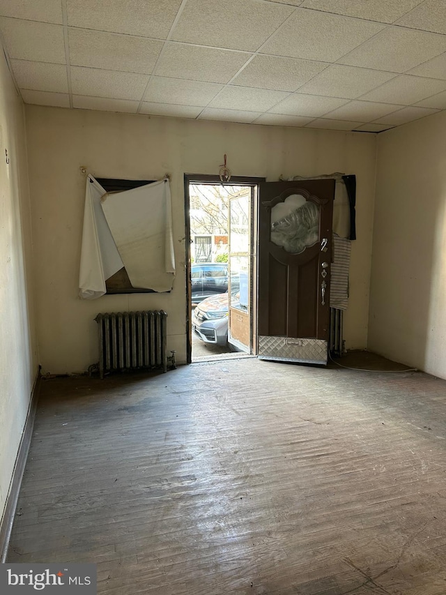 empty room featuring radiator, a paneled ceiling, and wood finished floors